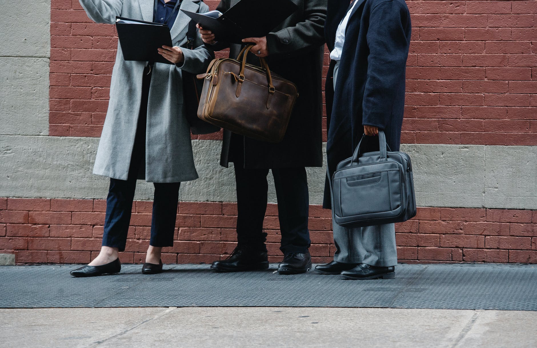 anonymous people in formal clothes reading documents on street