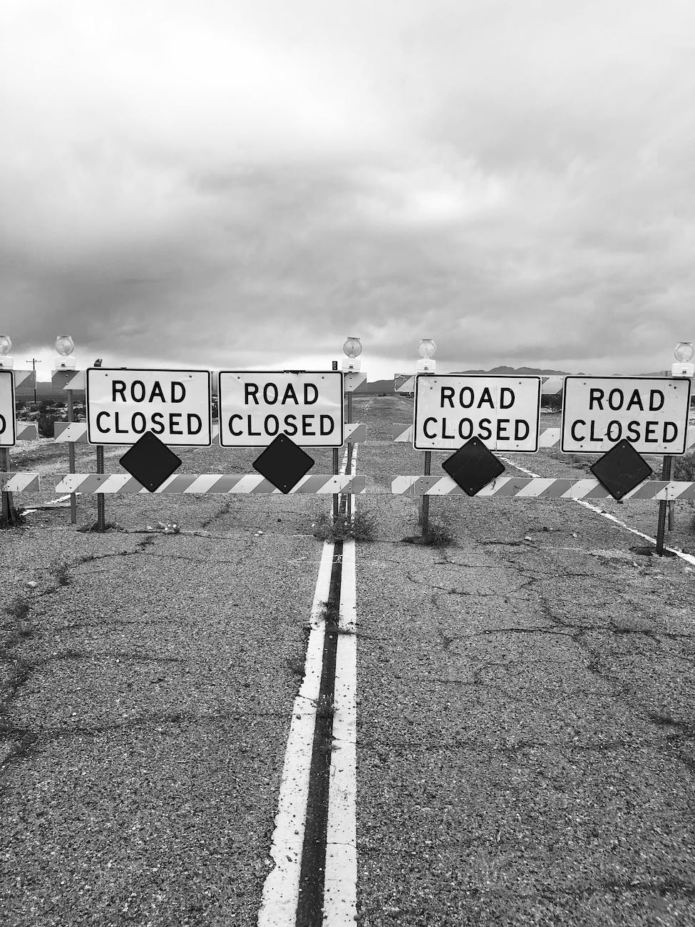 black and white photo of road with road closed signs